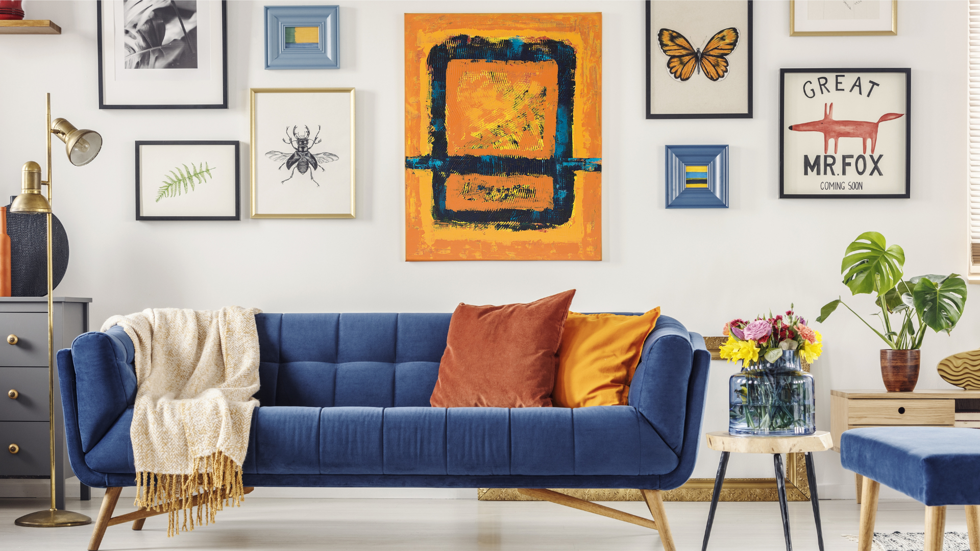 Modern, artsy living room with blue sofa and complementary orange throw pillows