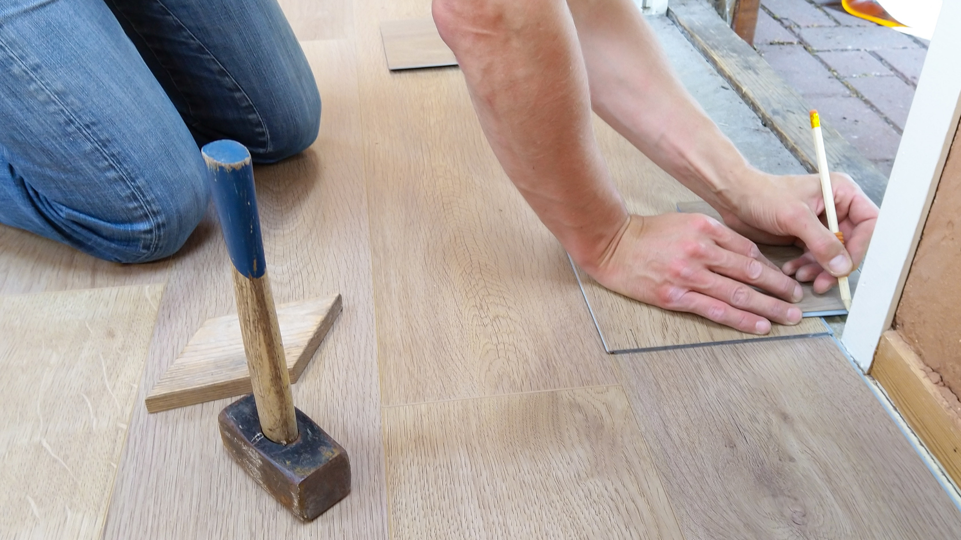 A flooring contractor measures wood-look LVP flooring to be cut and installed