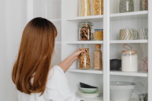 Woman in white shirt holding clear glass pantry jar
