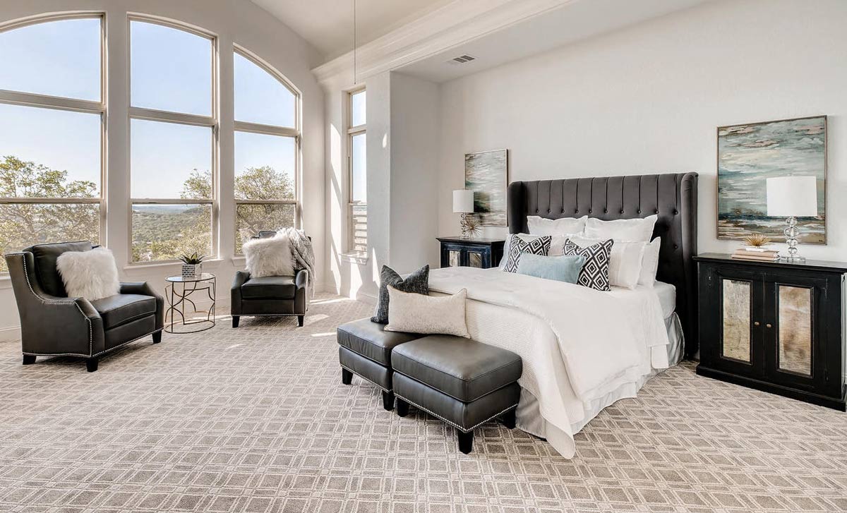 A vacant home staging of a modern master bedroom suite with black furniture and blue and white accent decor