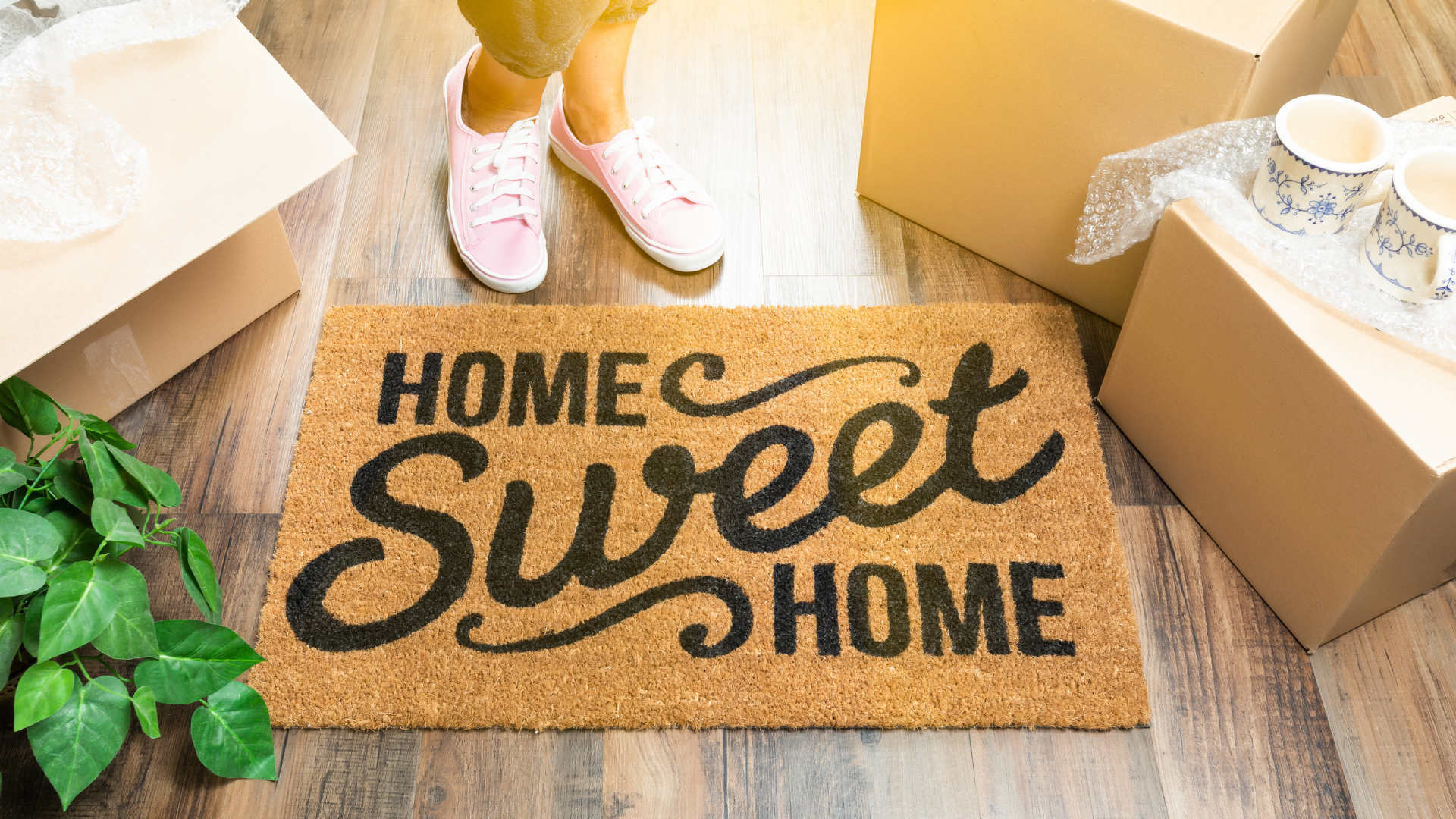 Should I buy a house in 2023? Person moving into new home with 'Home Sweet Home' mat