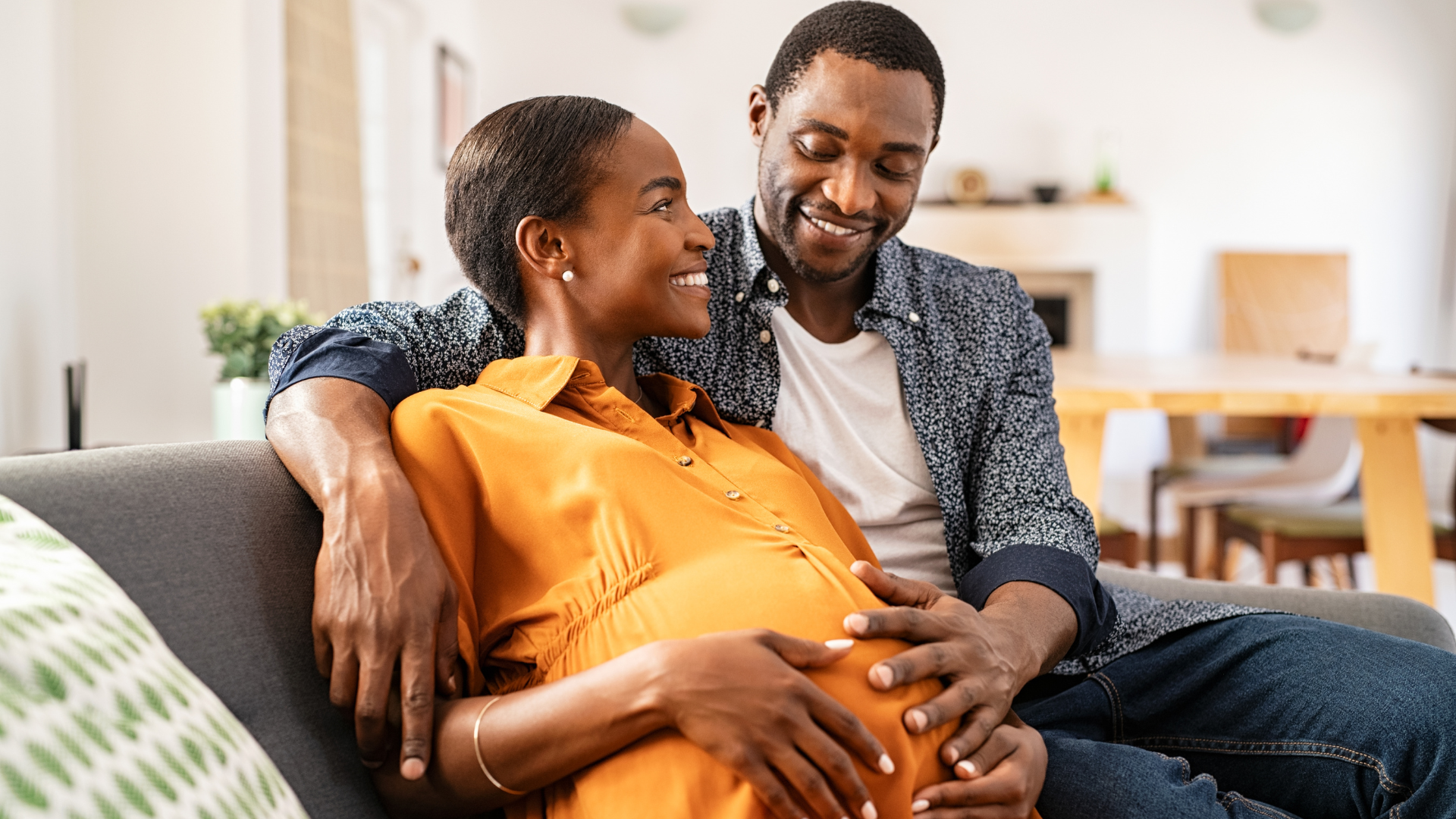 Pregnant black couple embracing happily deciding 'should I buy a house in 2023?'
