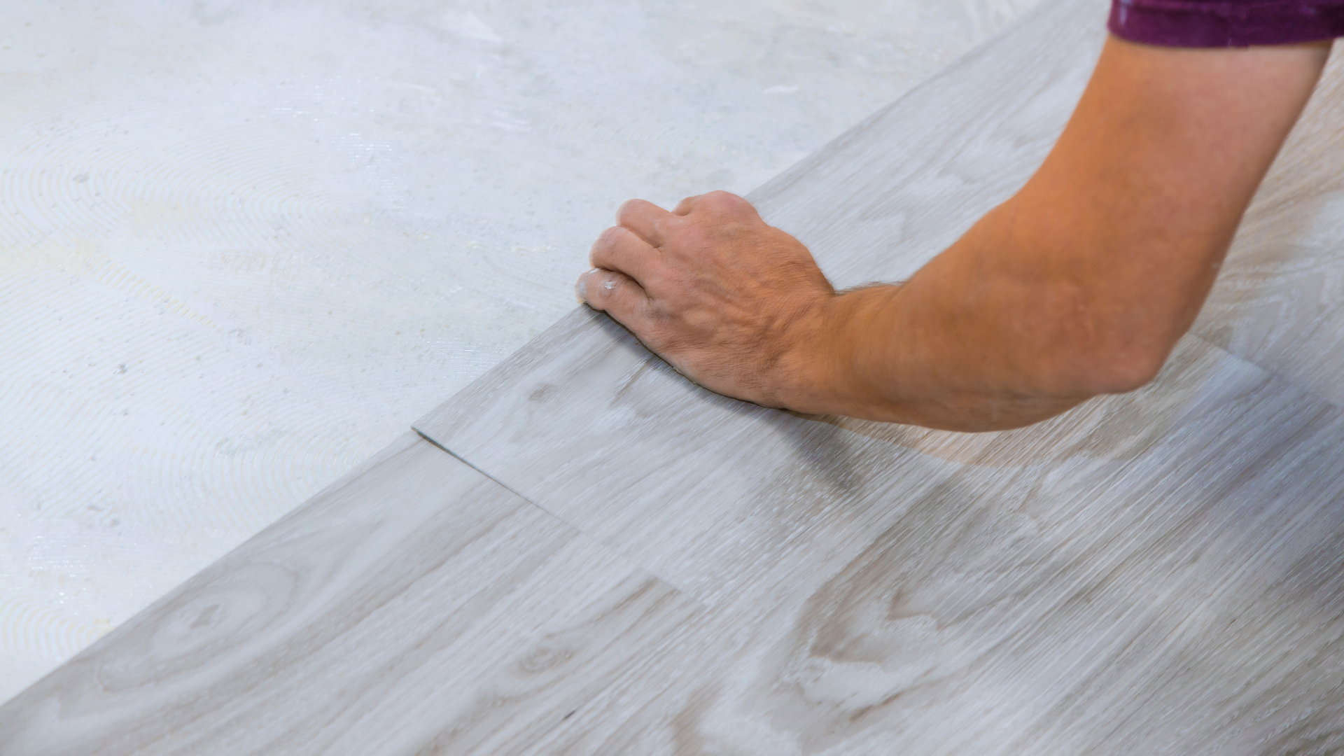 Wear-Layer Thickness LVP Flooring installer laying luxury vinyl planks on concrete subfloor